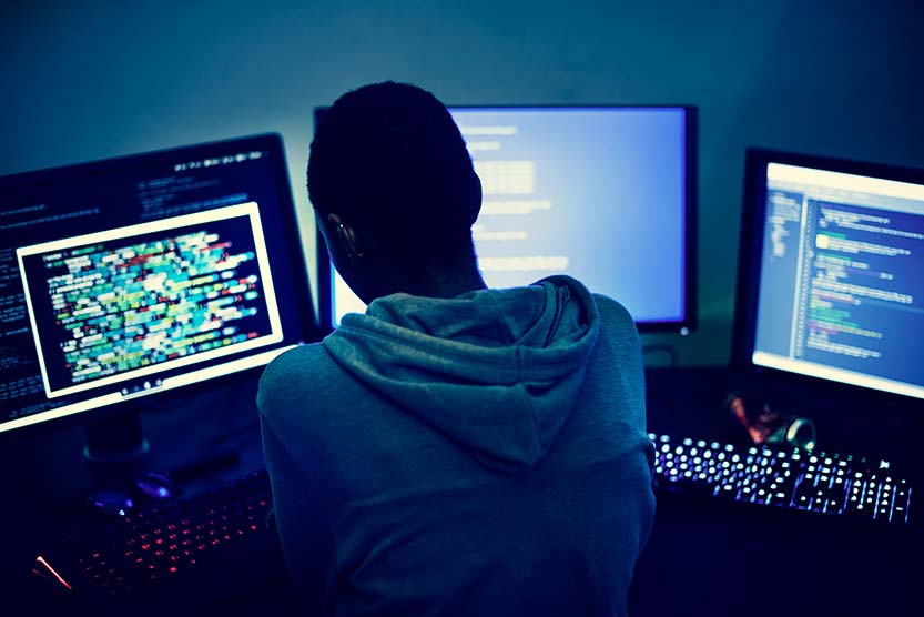 Image of technician working at three monitors - Educating people is a huge part of any small business cyber security plan